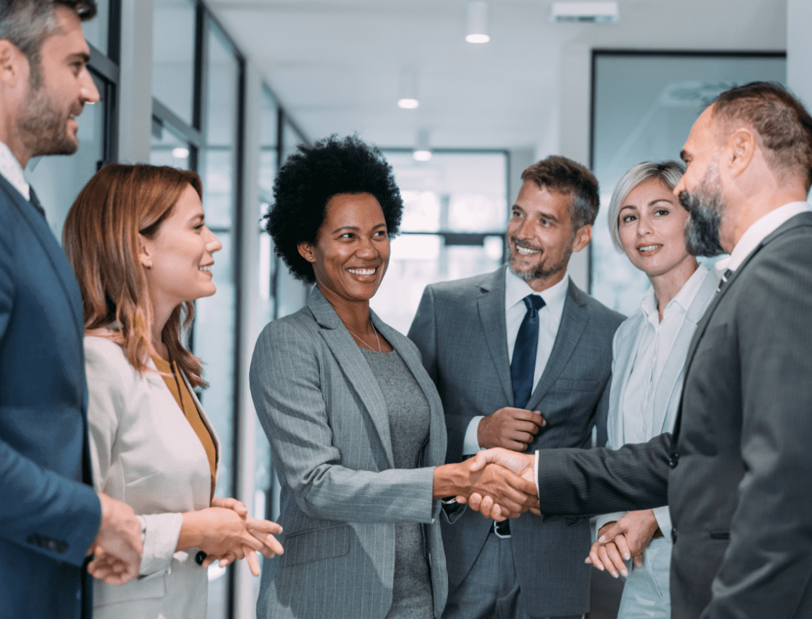 Business professionals shaking hands in office hallway.