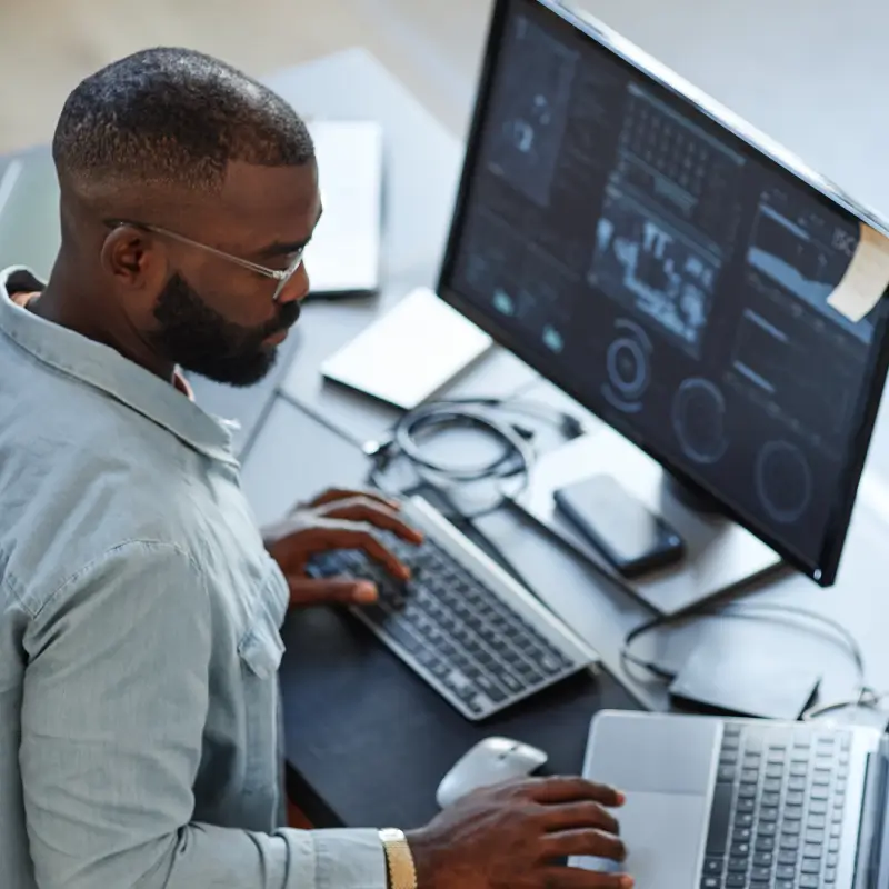 Man working on video editing at his desk with computer and laptop.